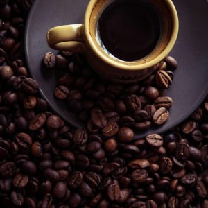 a cup of coffee sitting on top of a pile of coffee beans