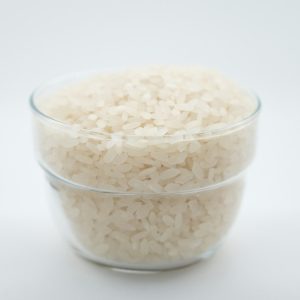 a glass bowl filled with rice on top of a white table